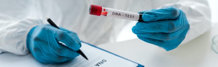 panoramic shot of scientist writing and holding test tube with lettering dna test