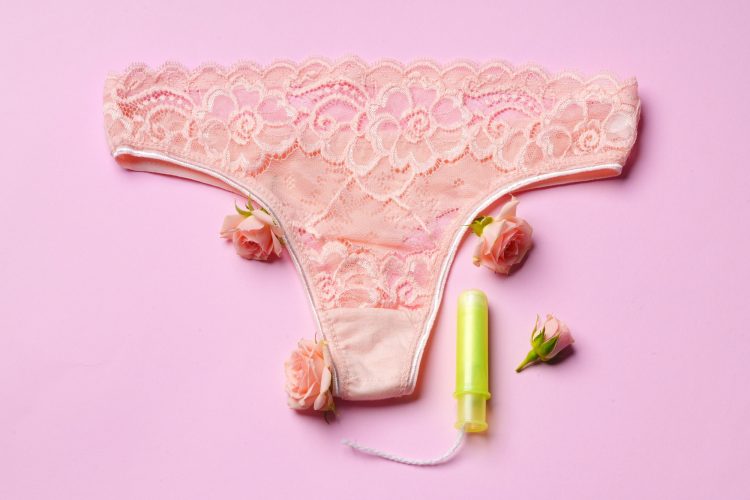 Women's panties with sanitary tampon on color background