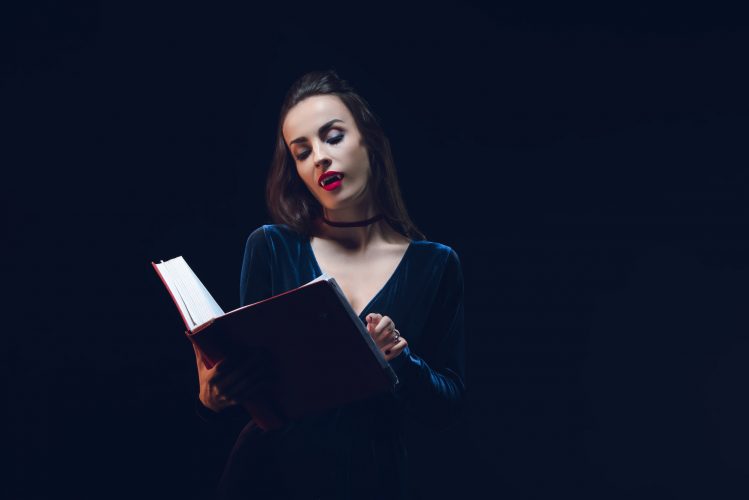 vampire woman reading magic book isolated on black