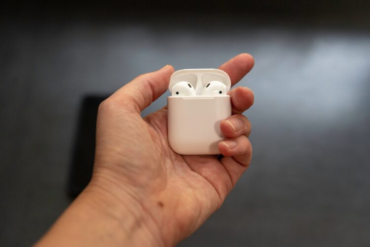 Wireless Apple AirPods headphones in palm of hand, close up view.