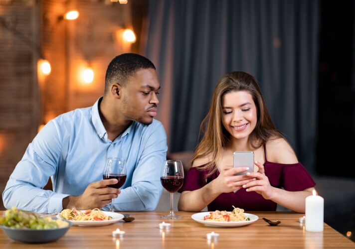Jealous black guy peeking into girlfriend's smartphone, reading her messages
