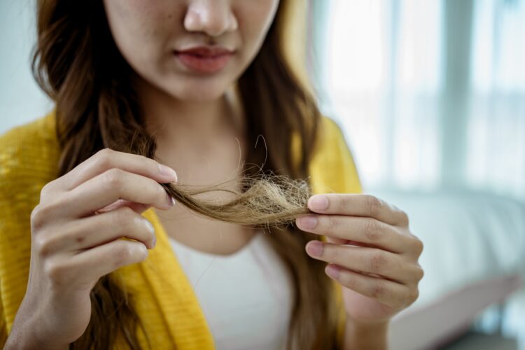 Young woman holding and looking her demaged hair.